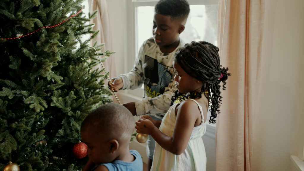 Uriah, Uziah, and Anaya Henry decorating the Christmas tree.